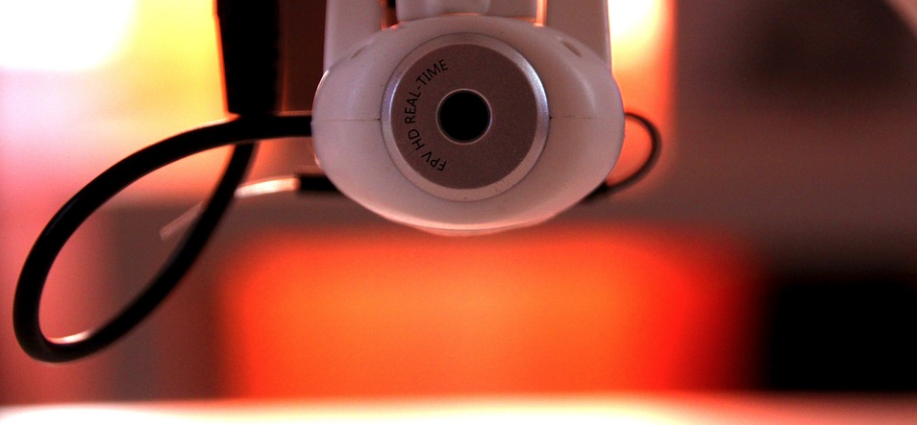 A small white spy camera with a cable